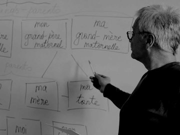 teacher at a whiteboard pointing to French words