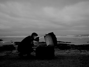 Woman opening a glowing treasure chest on an abandoned beach